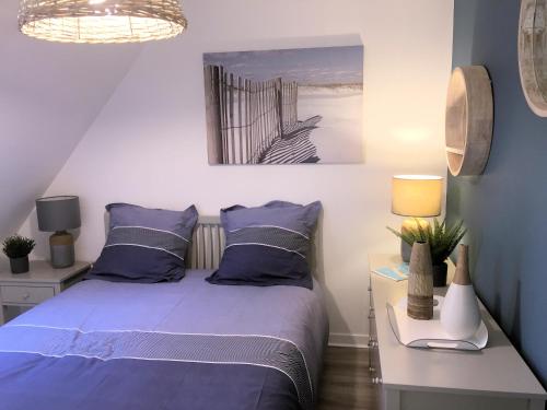 ein Schlafzimmer mit einem Bett mit blauen Kissen in der Unterkunft Cottage T3 à 5 minutes à pied de la plage in Le Pouliguen