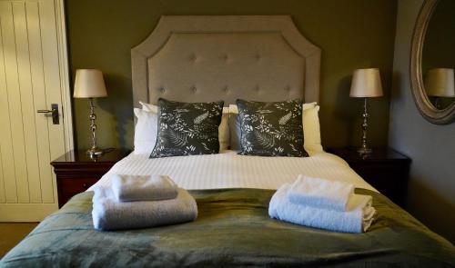 a bedroom with a large bed with two pillows at The Cottage in Willington