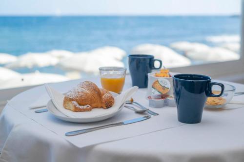 un tavolo con un piatto di prodotti da forno e tazze di succo d'arancia di Hotel Del Sole a Santa Marinella