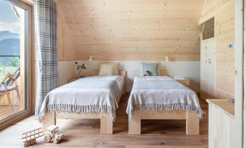 two beds in a room with a window at Domki Górski & Polny Kwiat in Zakopane