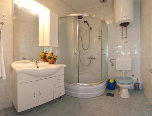 uma casa de banho com um chuveiro, um lavatório e um WC. em Apartment Firule Sandy Beach em Split
