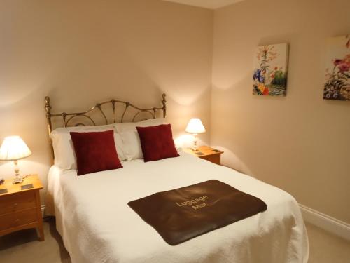 ein Schlafzimmer mit einem großen weißen Bett mit roten Kissen in der Unterkunft Oak End Lodge in Sevenoaks