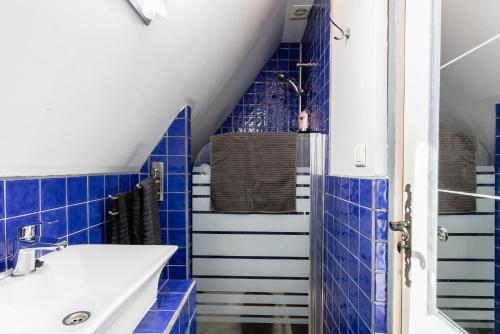 a bathroom with blue tiled walls and a sink at Gîtes Un Jardin dans la Falaise in Cabrerets
