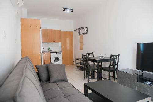 PaphosにあるRenovated one bedroom apartment in Paphos with poolのリビングルーム(ソファ、テーブル付)、キッチンが備わります。