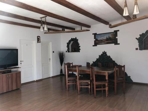 a dining room with a table and chairs and a tv at Pensiunea Bujor de Munte in Cîrţişoara