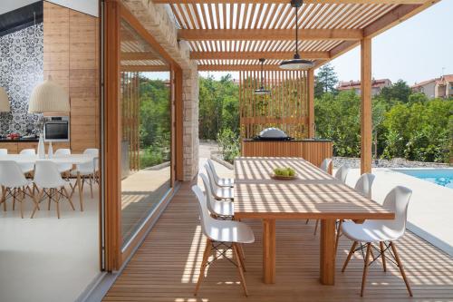 an outdoor dining area with a wooden table and white chairs at Villa Olea in Klimno