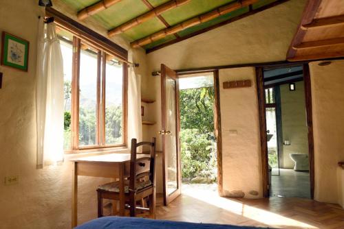 a bedroom with a bed and a table and windows at Avalon Hostal Boutique in Vilcabamba