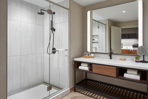 La salle de bains est pourvue d'une douche, d'un lavabo et d'un miroir. dans l'établissement The Watermark Hotel, à Tysons Corner