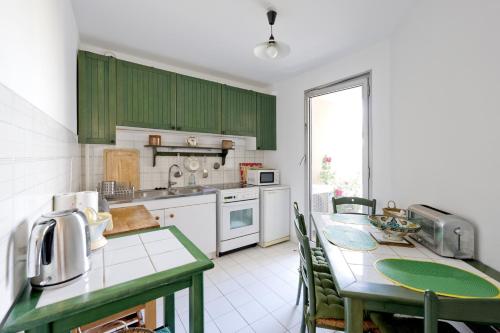 une cuisine avec des placards verts et une table avec des chaises dans l'établissement L'appart Beaubadat, à Bordeaux