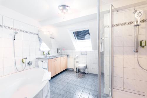 a bathroom with a tub and a shower and a toilet at Hotel am Park in Rust