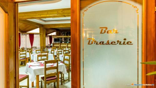 a restaurant with white tables and chairs and a bar characteristic at Anomis in Cîmpulung