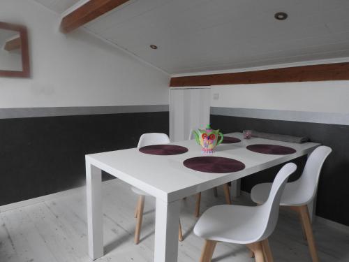 a white dining room table with four chairs and a vase on it at Appartement mansardé et climatisé 50 m2 in Pompignan