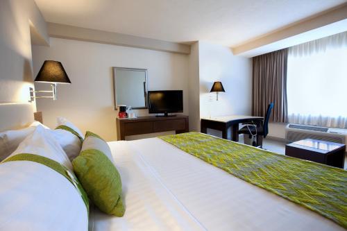 a hotel room with a large bed and a television at Holiday Inn Puebla La Noria by IHG in Puebla