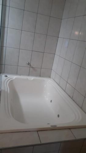 a white tub in a bathroom with white tiles at Sítio Santa Terezinha Canastra in São João Batista do Glória
