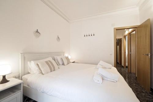 a white bedroom with a white bed with towels on it at Stay U-nique Apartments Tapioles in Barcelona