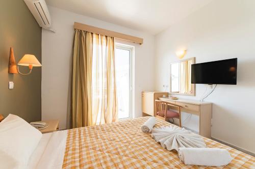 Pokój hotelowy z łóżkiem, biurkiem i telewizorem w obiekcie Summer View w mieście Theologos