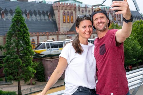a man and a woman taking a picture of a train at Hotel am Park in Rust