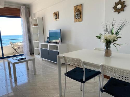 een woonkamer met een witte tafel en stoelen en de oceaan bij Quarteira Beach in Quarteira