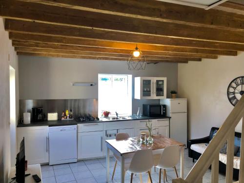 a kitchen with white cabinets and a table with chairs at La Vove in Rouillon