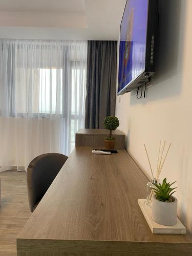 a living room with a large wooden table with a tv on the wall at Aqua Villa by the Sea in Eforie Sud