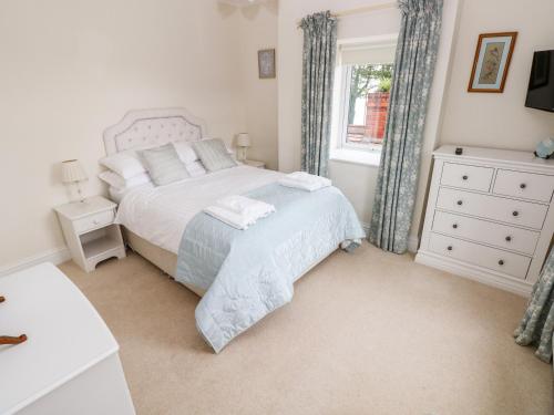 a bedroom with a white bed and a window at The Headlands - Gower in The Mumbles
