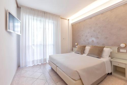 a bedroom with a white bed and a window at Hotel Feldberg in Riccione