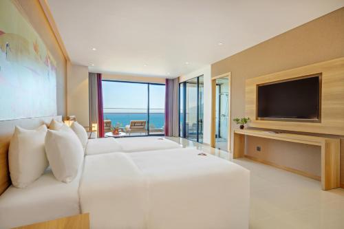 a white bedroom with a large bed and a television at Da Nang - Mikazuki Japanese Resorts & Spa in Da Nang