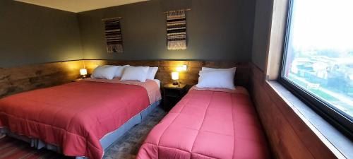 two beds sitting in a room with a window at Hostal Esquina Patagónica in Coihaique