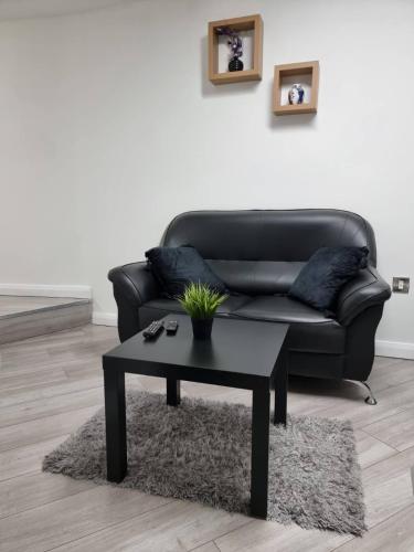 a living room with a black couch and a table at Bvapartments-Queensgate in Huddersfield