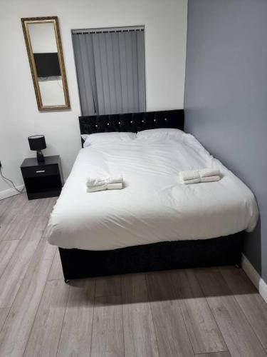 um quarto com uma cama com lençóis brancos e um espelho em Bvapartments-Queensgate em Huddersfield