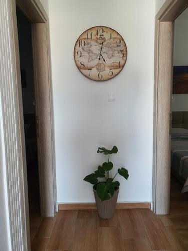 a clock hanging on a wall next to a potted plant at Villa Fer Forze you have the feeling of your own holiday home in Asprovalta