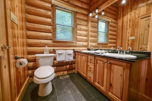 a log cabin bathroom with a toilet and a sink at Grande Forêt by Tremblant Platinum in Mont-Tremblant
