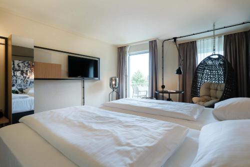 a hotel room with two beds and a flat screen tv at Seminaris Hotel Bad Boll in Bad Boll