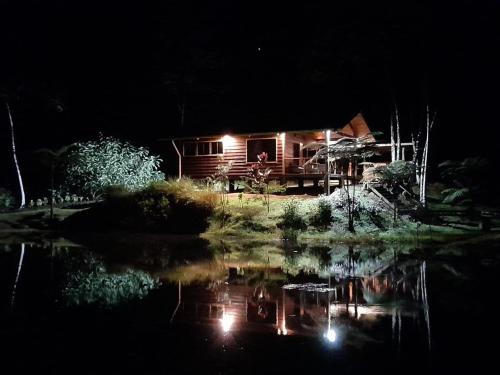 a log cabin at night with a reflection in the water at Mei Tai Cacao Lodge in Bijagua