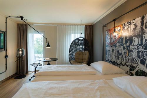 a bedroom with a large bed and a chair at Seminaris Hotel Bad Boll in Bad Boll