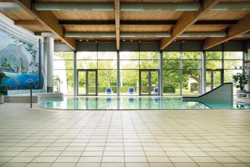 an indoor pool with glass windows and a tile floor at Seminaris Hotel Bad Boll in Bad Boll