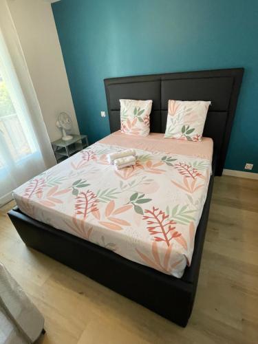 a bed with a black frame with a pink and green blanket at Chambre proche du centre-ville in Montpellier