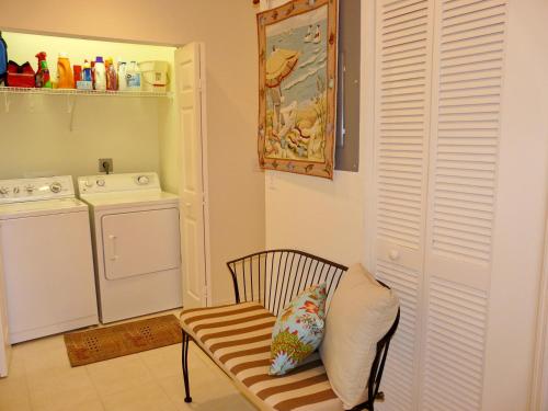uma cozinha com uma máquina de lavar roupa e uma cadeira com uma almofada em 265 Villas at Waterside, Unit 201 em Marco Island