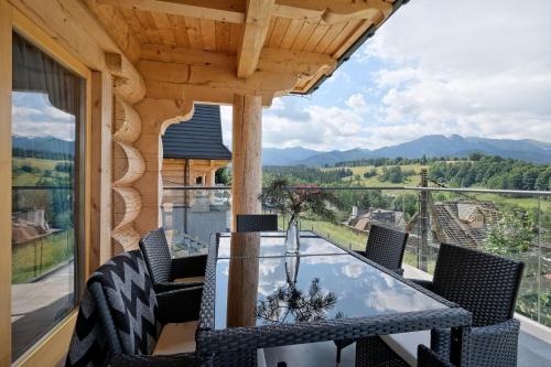 a dining room with a glass table and chairs on a balcony at Osada Bachledzki Wierch Odkryj Zakopane in Zakopane