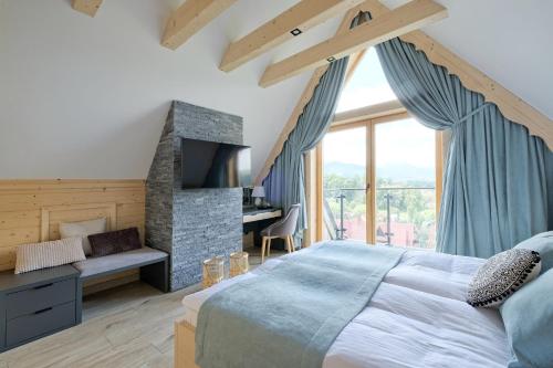 a bedroom with a large bed and a stone fireplace at Osada Bachledzki Wierch Odkryj Zakopane in Zakopane