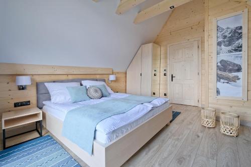 a bedroom with a bed and a wooden wall at Osada Bachledzki Wierch Odkryj Zakopane in Zakopane