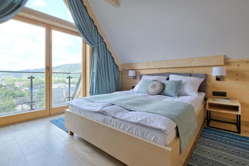 a bedroom with a large bed and a large window at Osada Bachledzki Wierch Odkryj Zakopane in Zakopane