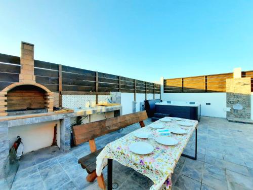 eine Terrasse mit einem Tisch, Bänken und einem Pizzaofen in der Unterkunft Canary Wild House 2 in Carrizal