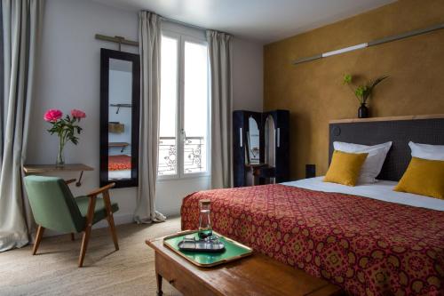 ein Hotelzimmer mit einem Bett, einem Tisch und einem Fenster in der Unterkunft Hôtel La Nouvelle République & Hammam in Paris