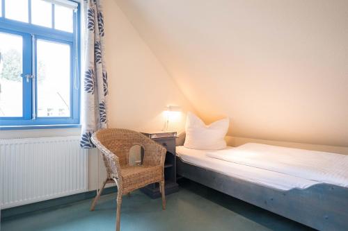 een slaapkamer met een bed, een stoel en een raam bij Ferienhaussiedlung Strandperlen Sanddornhof 5a (Typ IV) in Wustrow