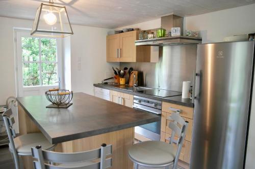 a kitchen with a stainless steel refrigerator and wooden cabinets at 700m de la plage des Dames - Maison pour 9 in Noirmoutier-en-l'lle