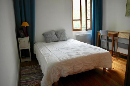 a bedroom with a bed and a table and a window at 700m de la plage des Dames - Maison pour 9 in Noirmoutier-en-l'lle