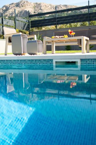 a swimming pool with chairs and a table next to a swimming pool at Villa Aurora in Baška