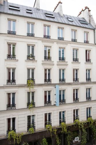 a large white building with a lot of windows at Hôtel La Nouvelle République & Hammam in Paris