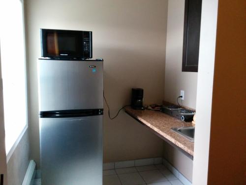 a microwave sitting on top of a refrigerator in a kitchen at Bonnyville Hotel in Bonnyville